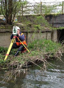 Surveyor with instrument by watercourse